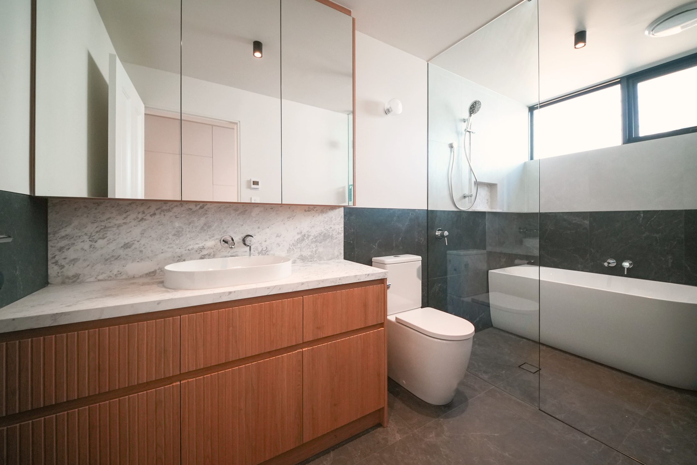 Bathroom with a fluted timber vanity, marble top, freestanding bath and walk-in shower