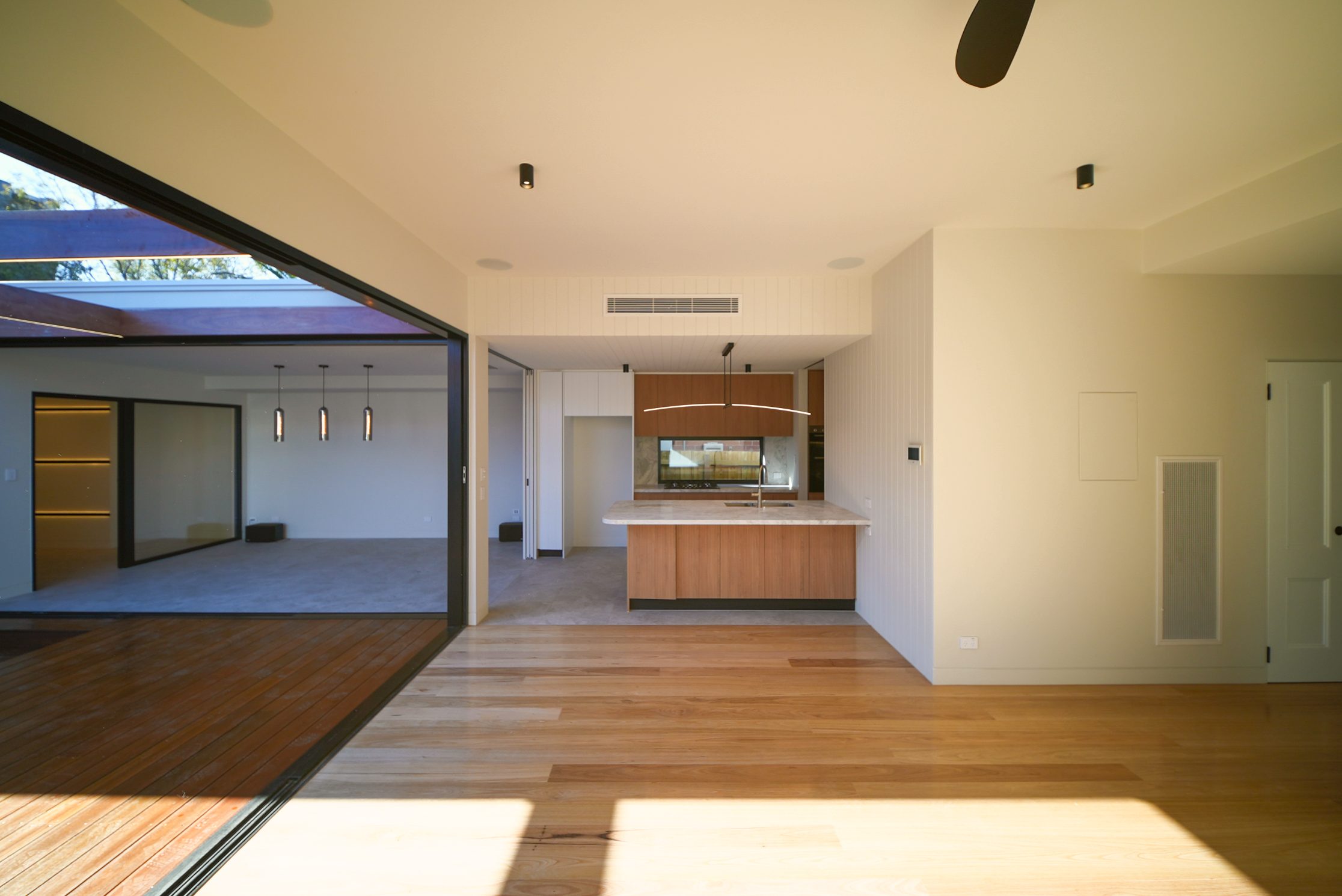 Living room opening to the deck, with views through to the rumpus room and timber kitchen