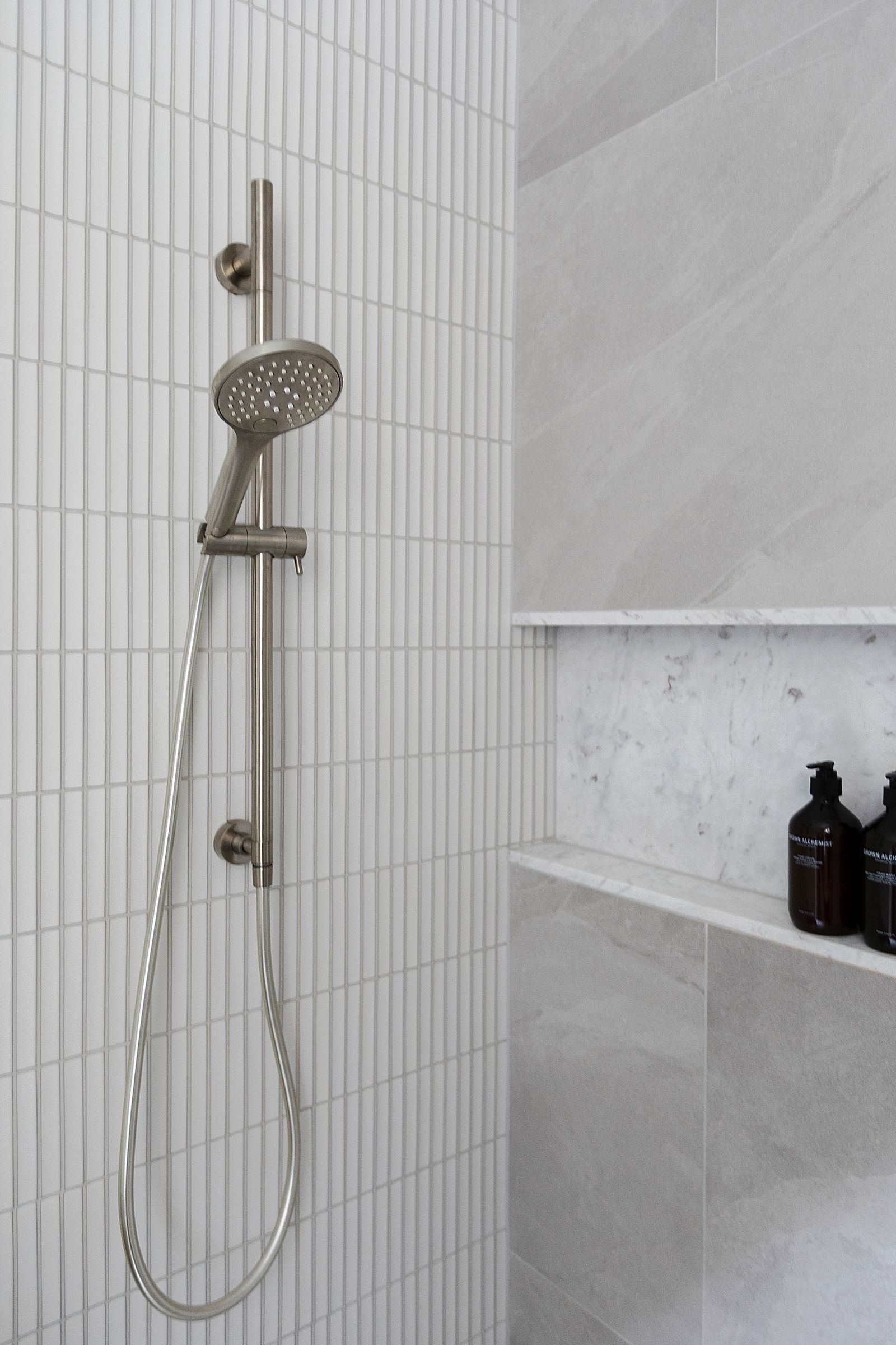 Hand shower on a rail against vertical finger tiles