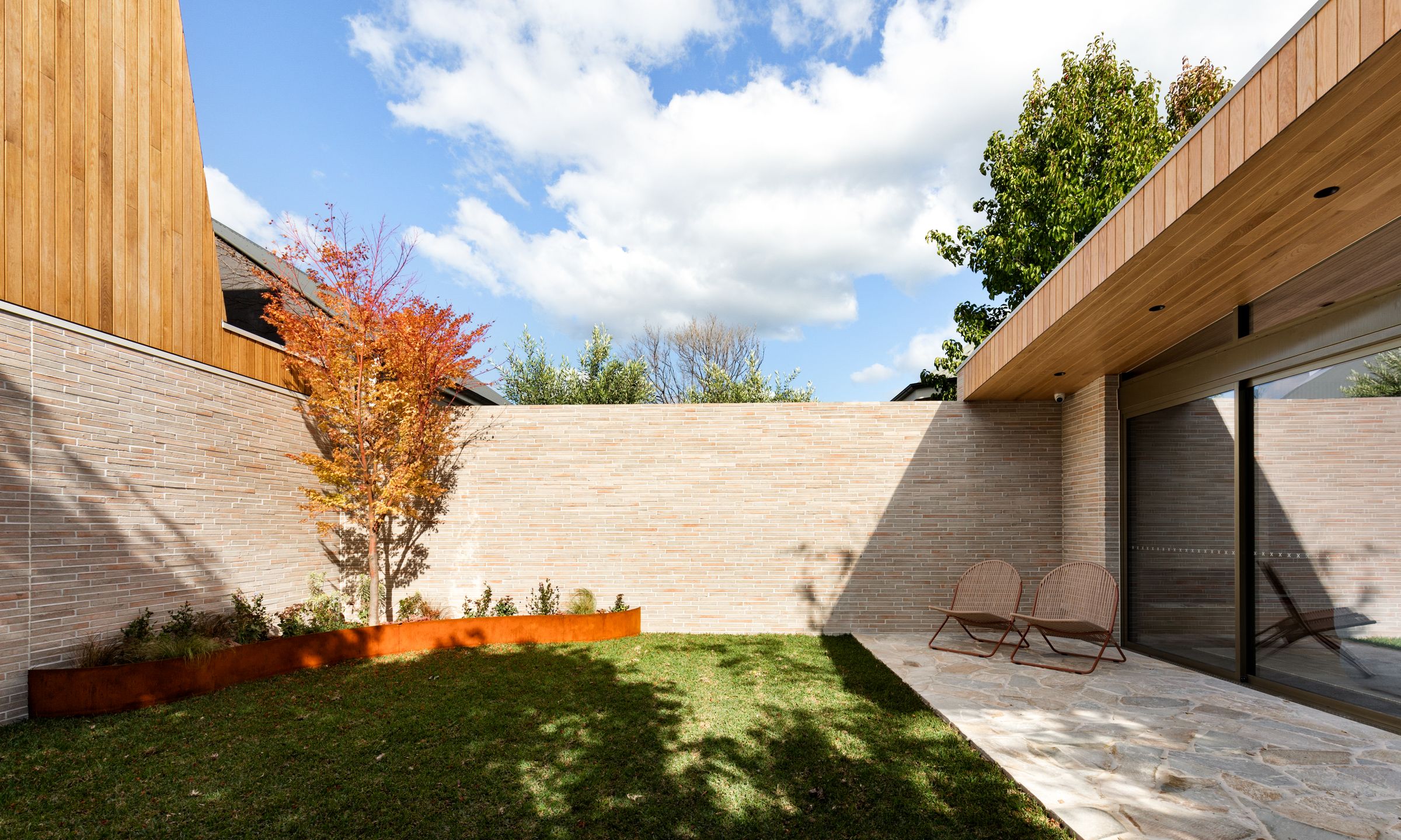 Brick-walled courtyard with a Japanese maple and corten planter