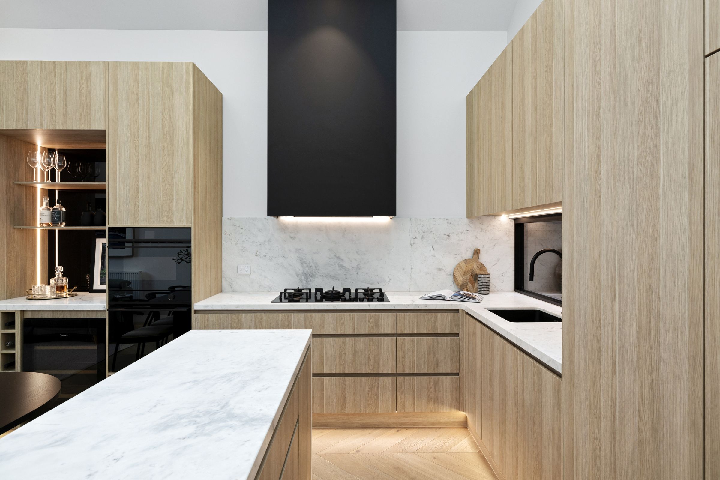 Floor-to-ceiling oak joinery with a slatted bulkhead, slot window and banquette