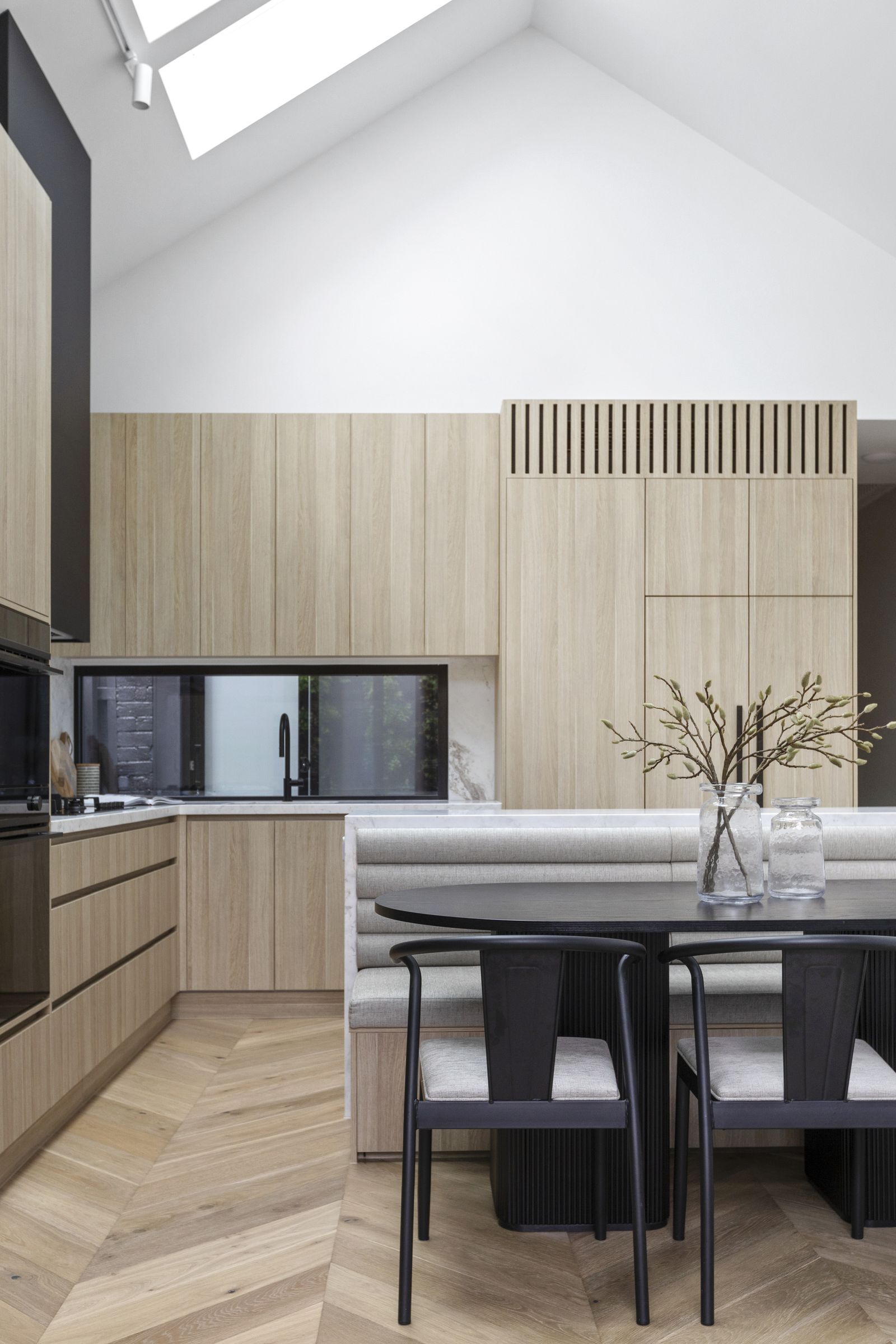 Kitchen and banquette dining beneath a vaulted ceiling and skylight