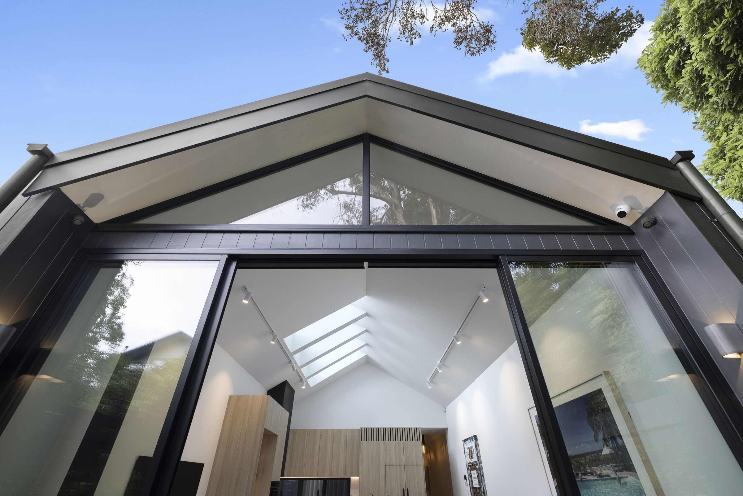 The rear gable from the courtyard, with black cladding, a glazed apex and sliding doors into the vaulted living space