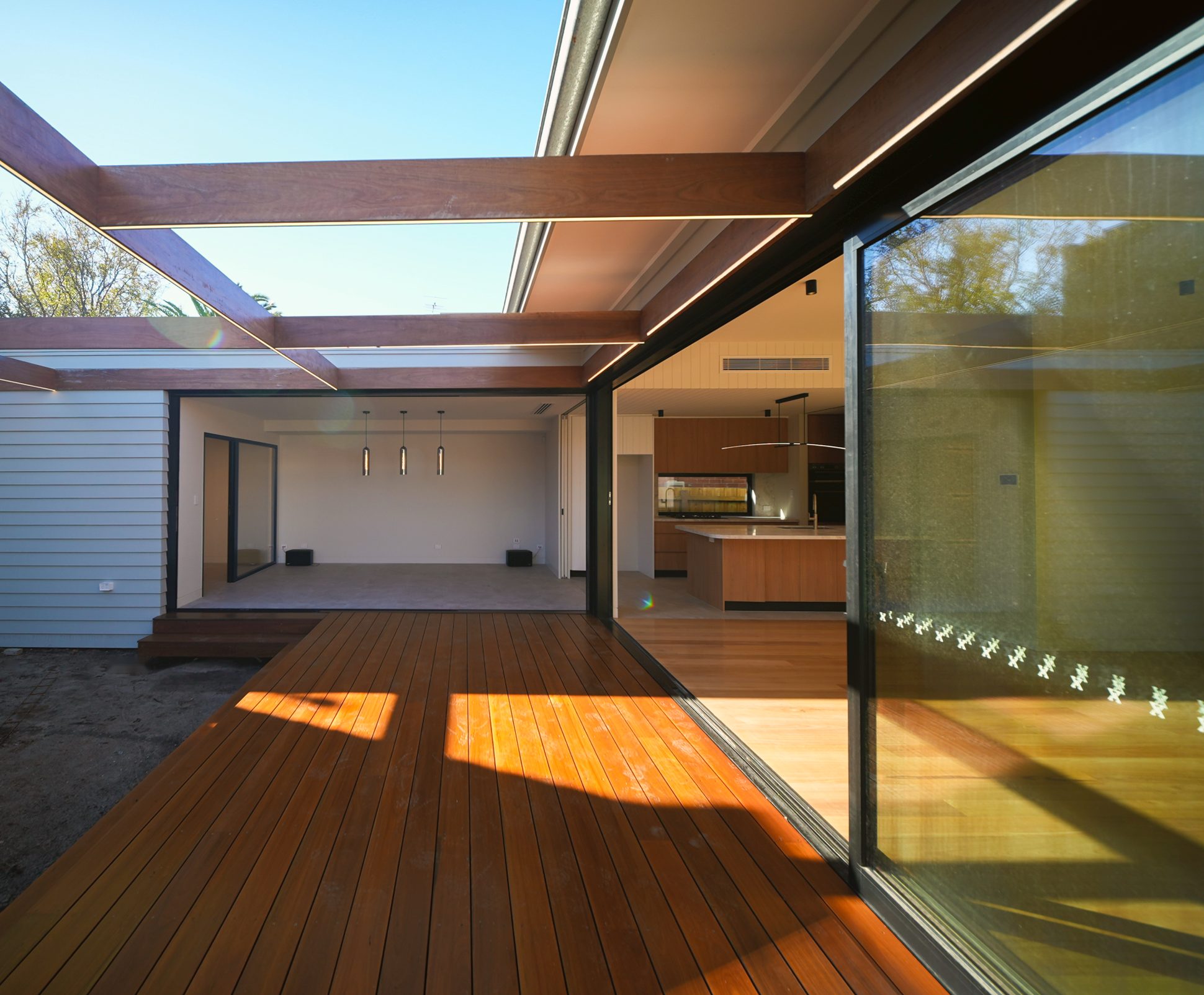 Timber deck leading to the rumpus room, beneath pergola beams with concealed lighting