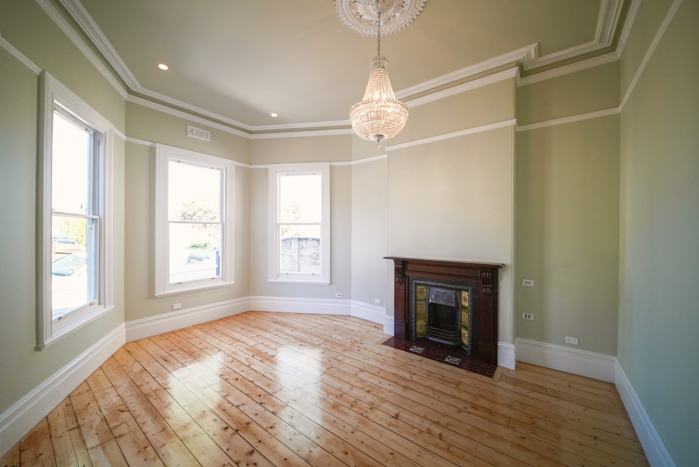 Front room with a bay window, crystal chandelier, ceiling rose, timber mantel and original timber floors