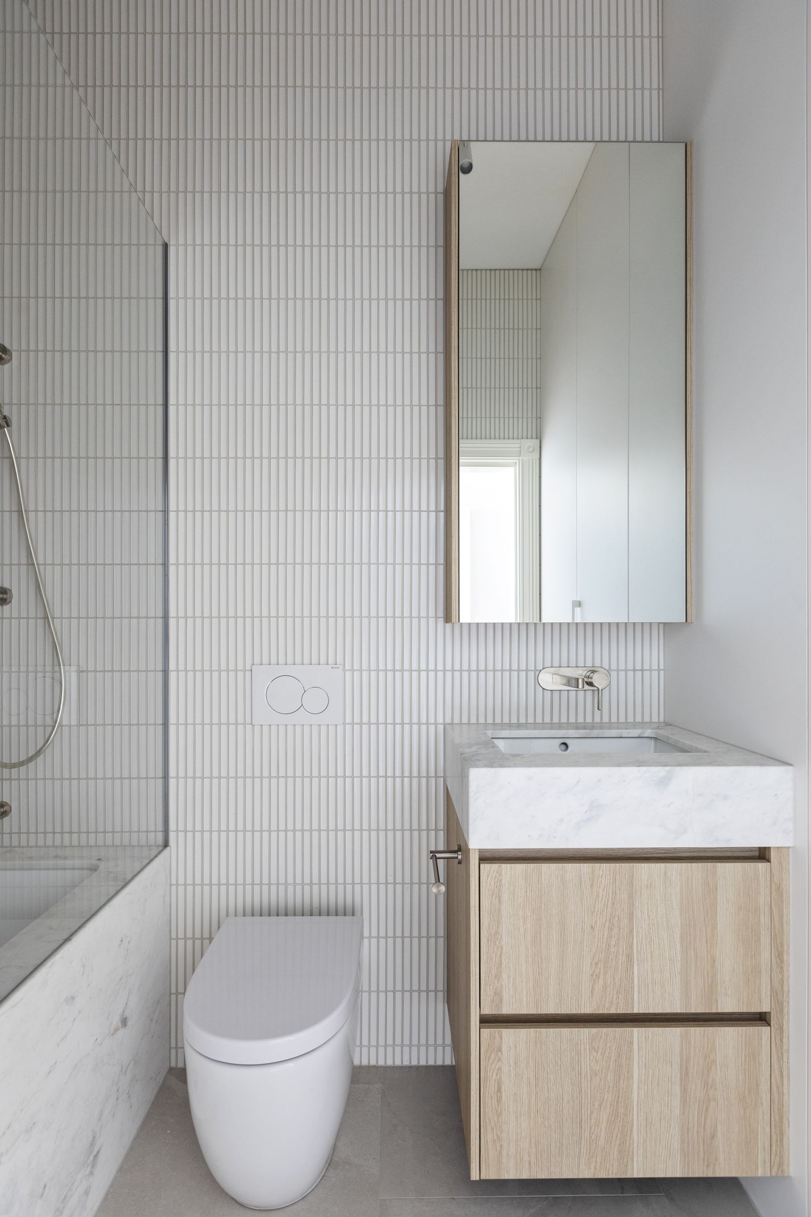Bathroom with white finger tiles, marble vanity top and oak drawers