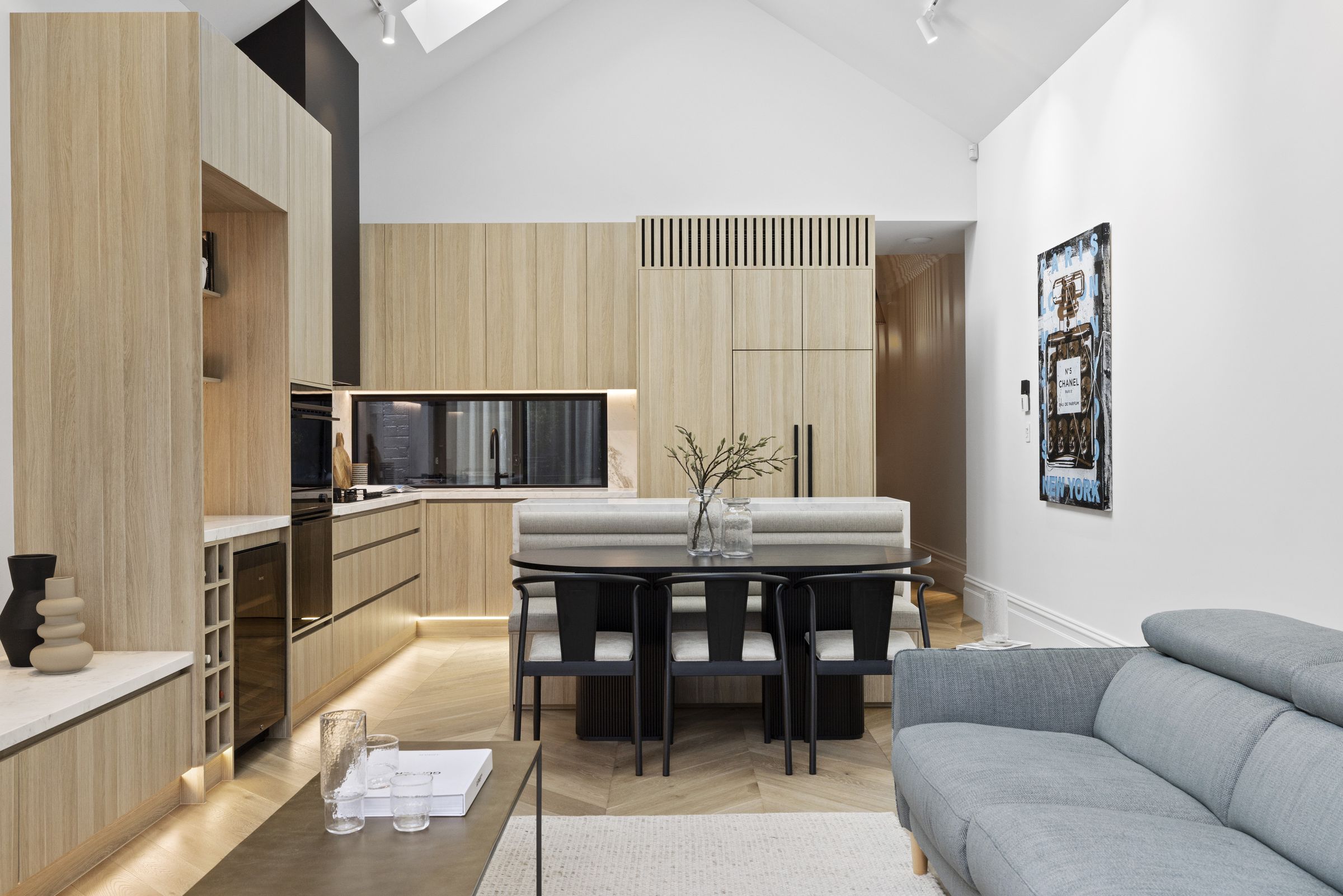 Open-plan kitchen, banquette dining and living beneath a vaulted ceiling and skylight