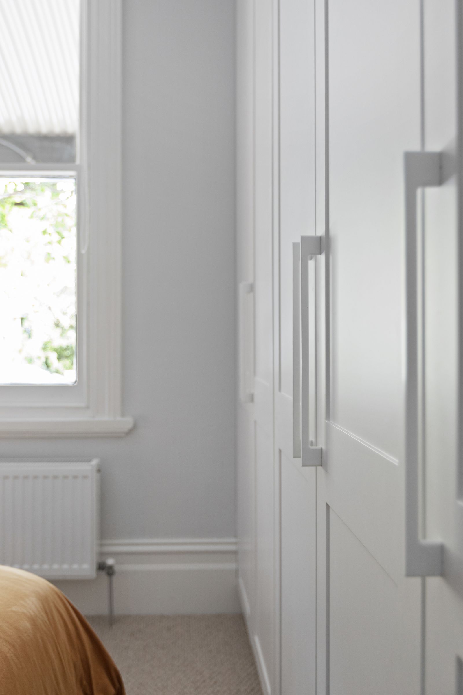 Detail of wardrobe handles beside a sash window