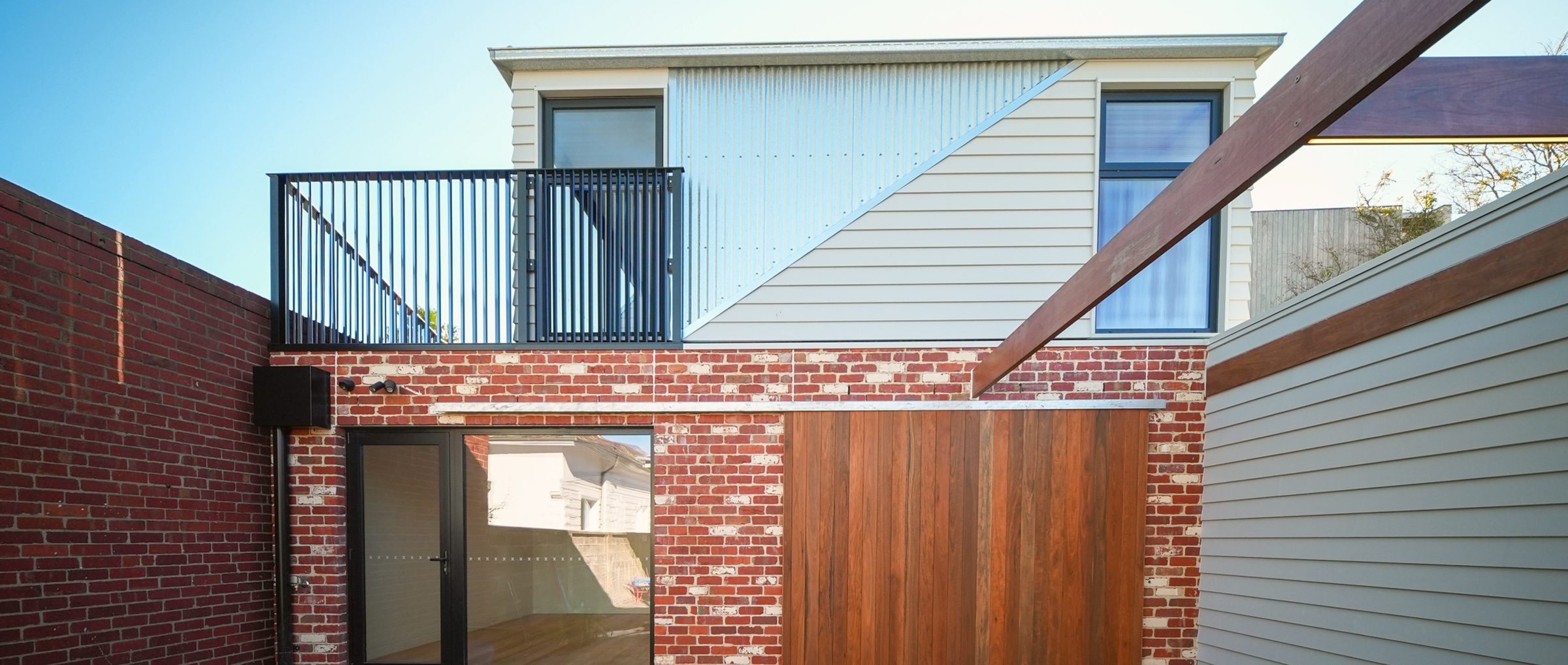 The rear of the house: recycled red brick, a hardwood screen and an upper level with a balcony