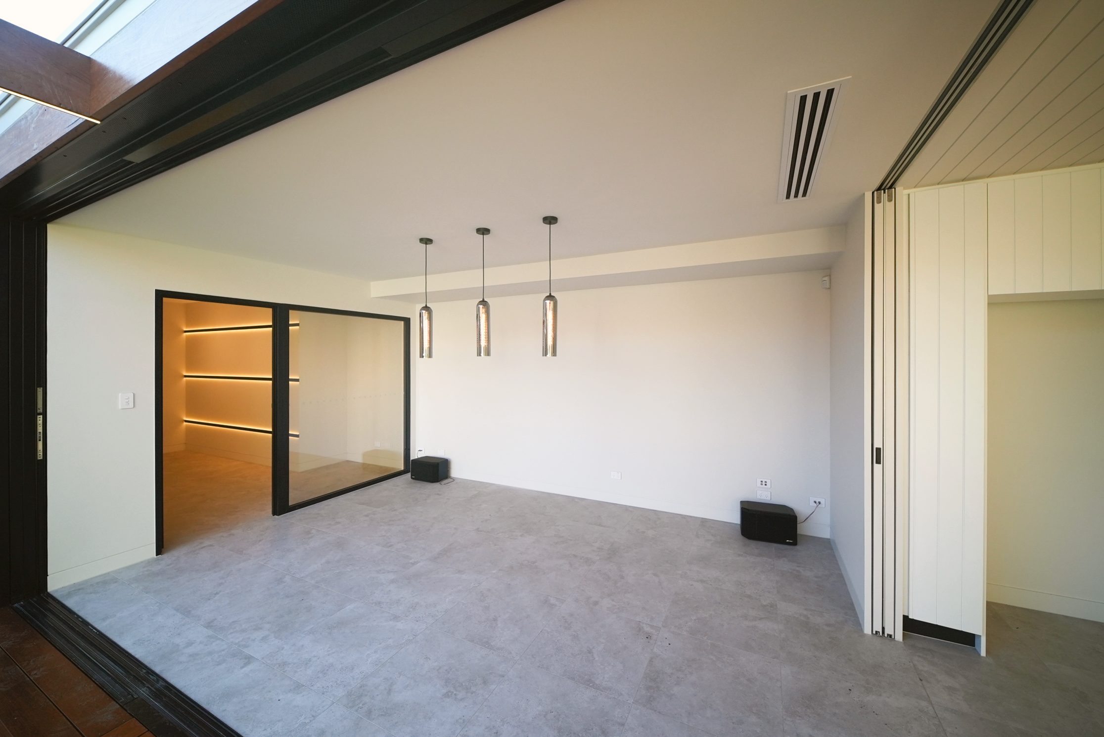 Rumpus room with stone-look tiles, glass pendants and a glazed wall to the gallery room