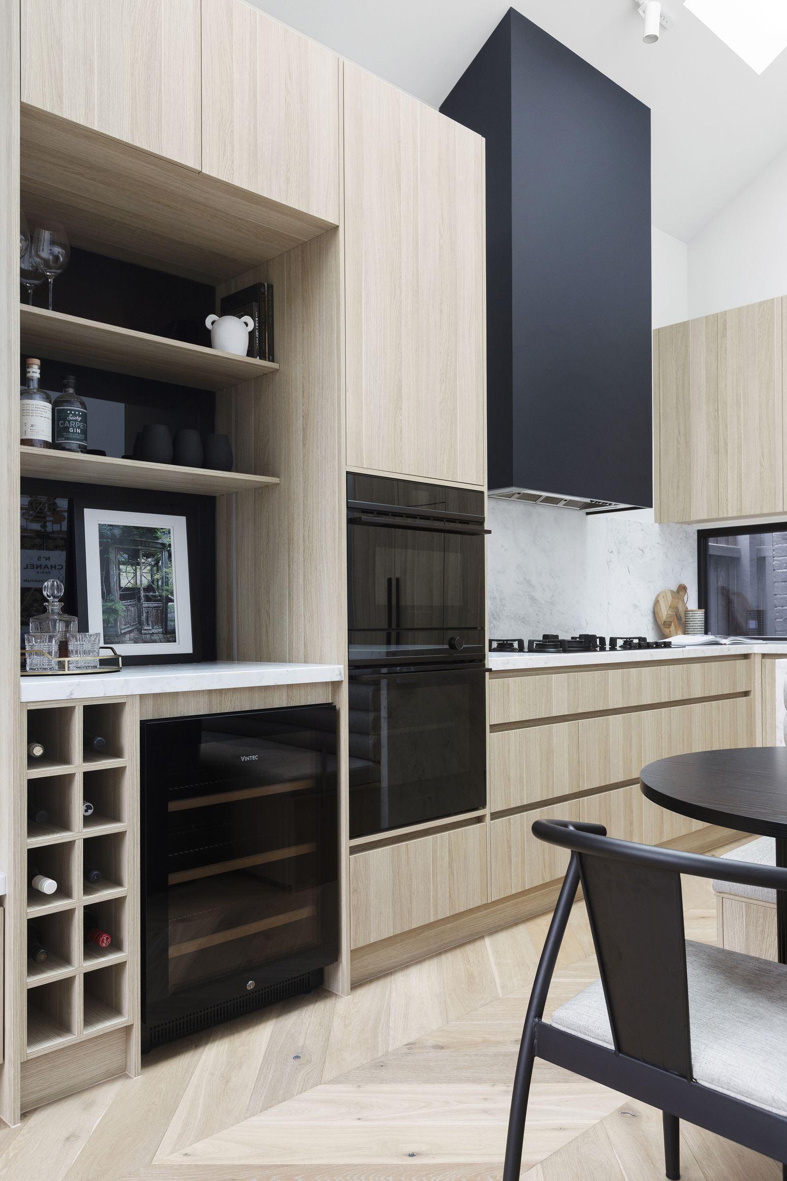 Oak joinery with a bar niche, wine fridge, wine rack and integrated ovens