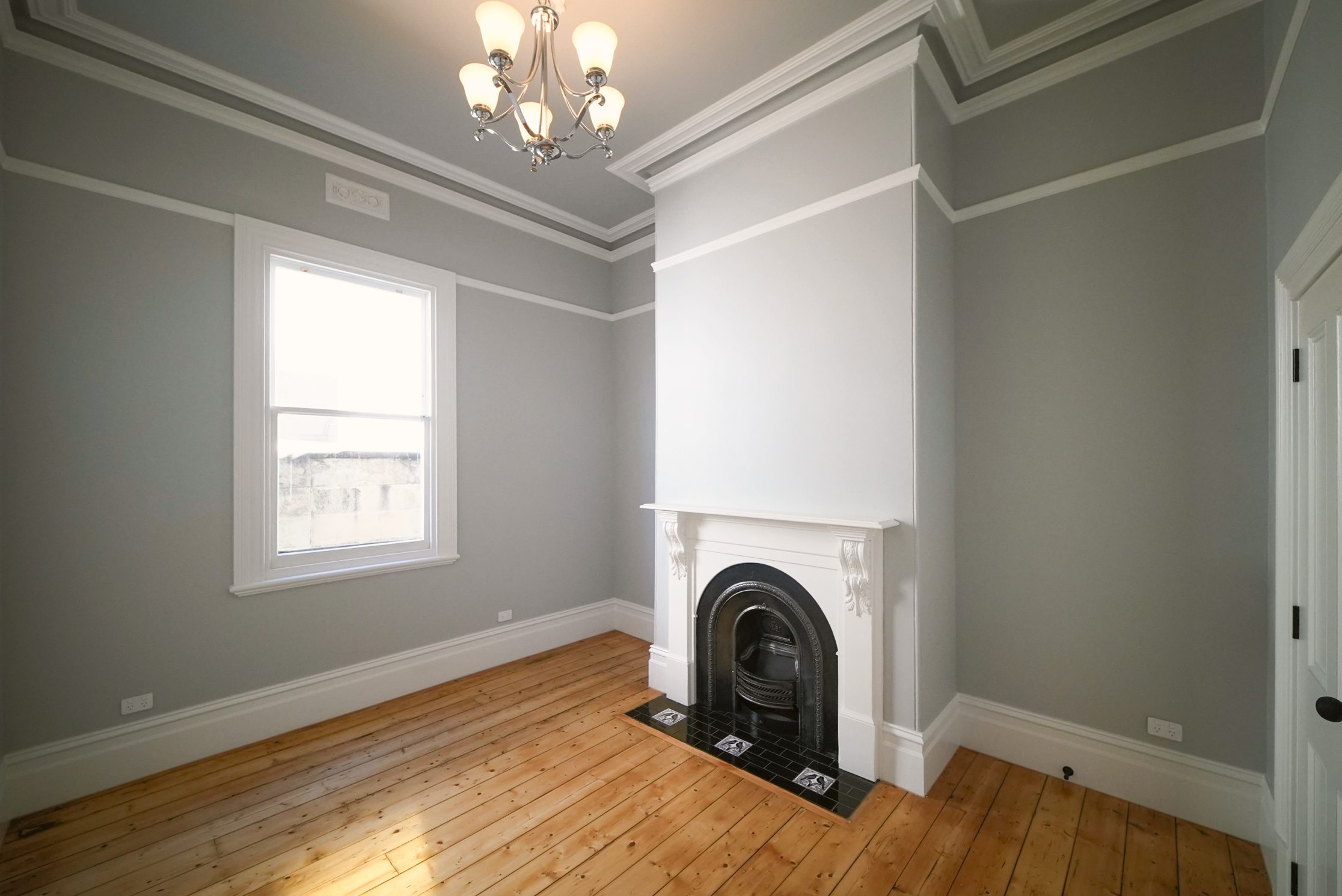 Bedroom with ornate cornices, a restored cast iron fireplace and timber floors