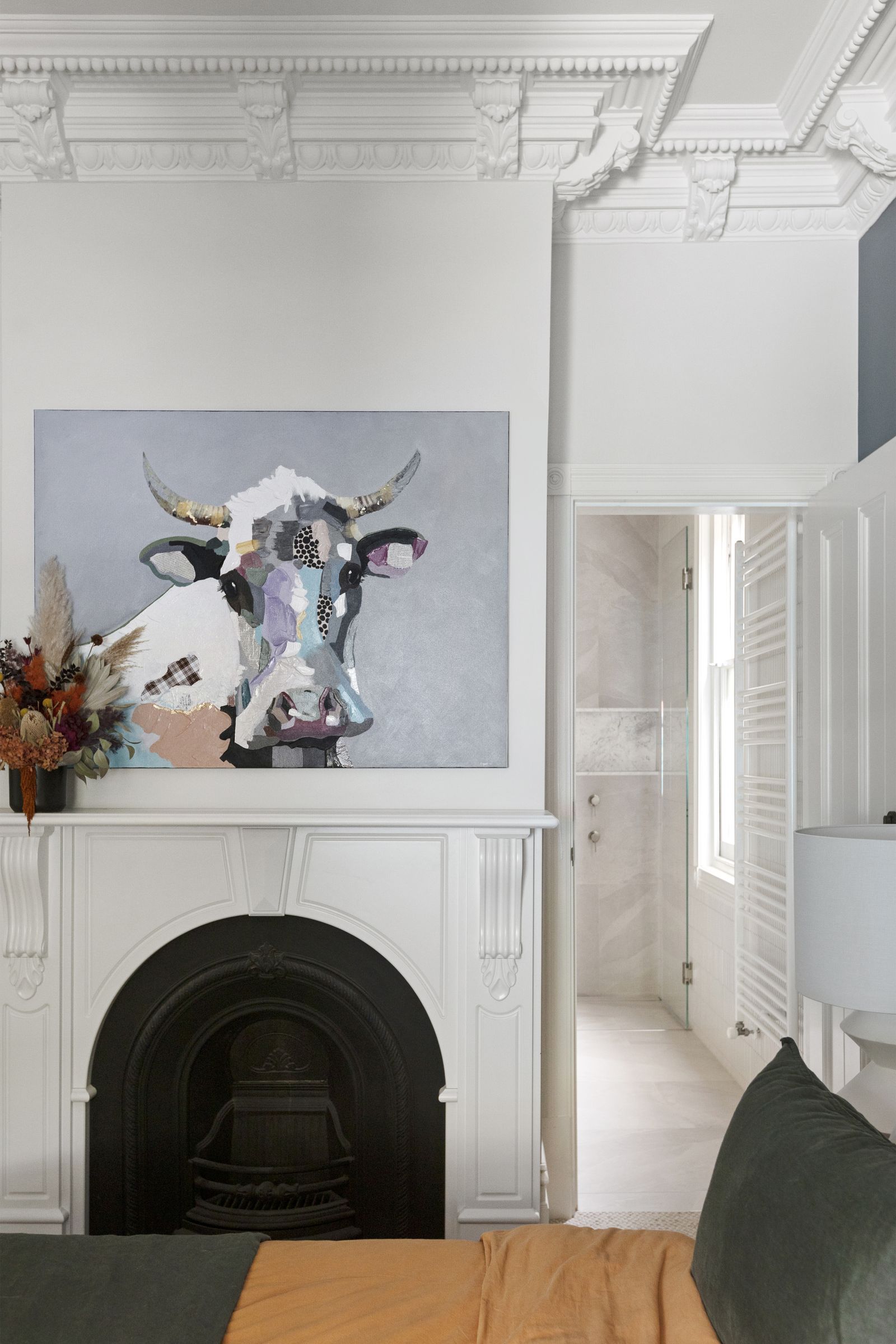 Bedroom with an ornate cornice, restored arched fireplace and a view through to the ensuite