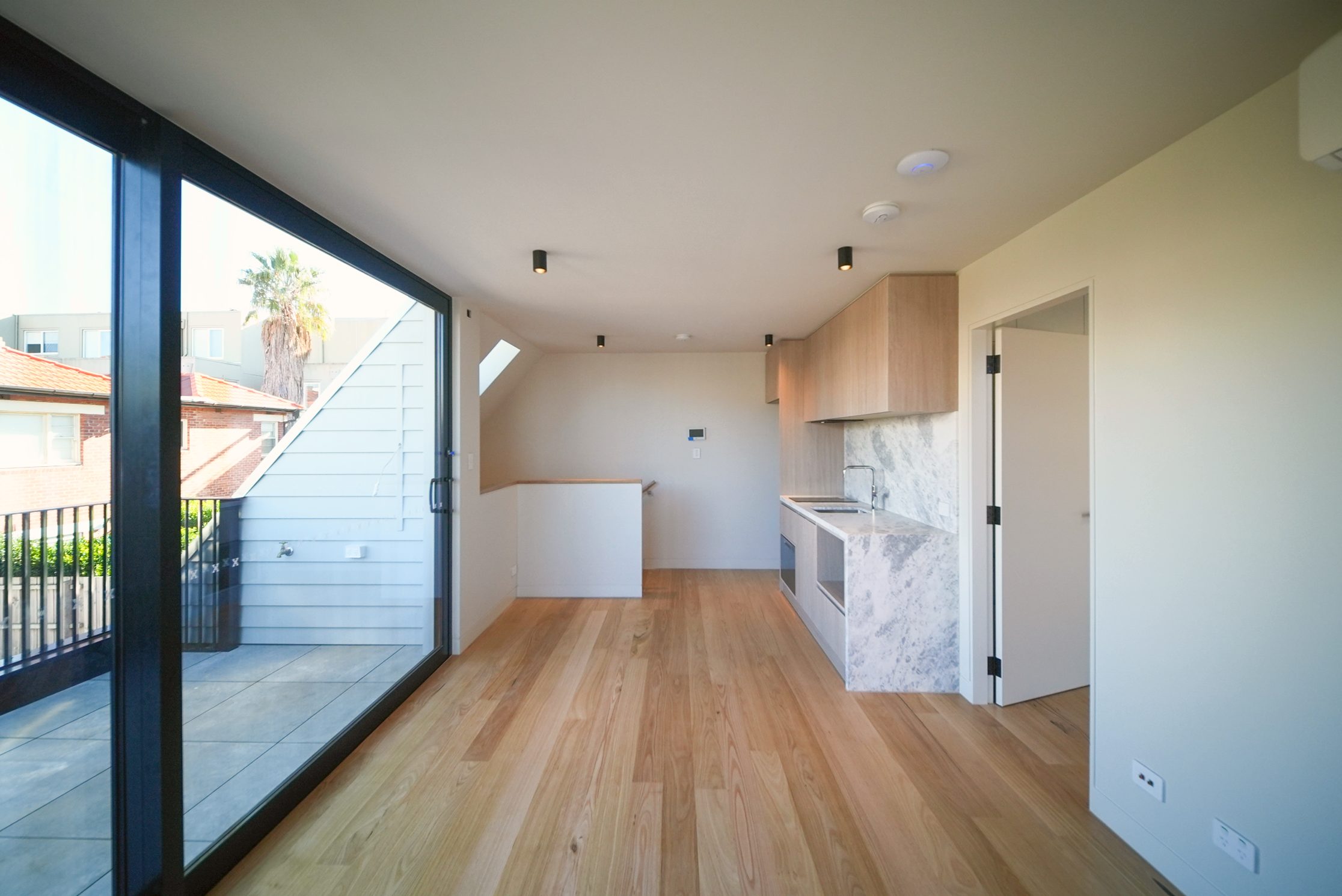 Upstairs living space opening to a terrace, with a kitchenette in stone and timber