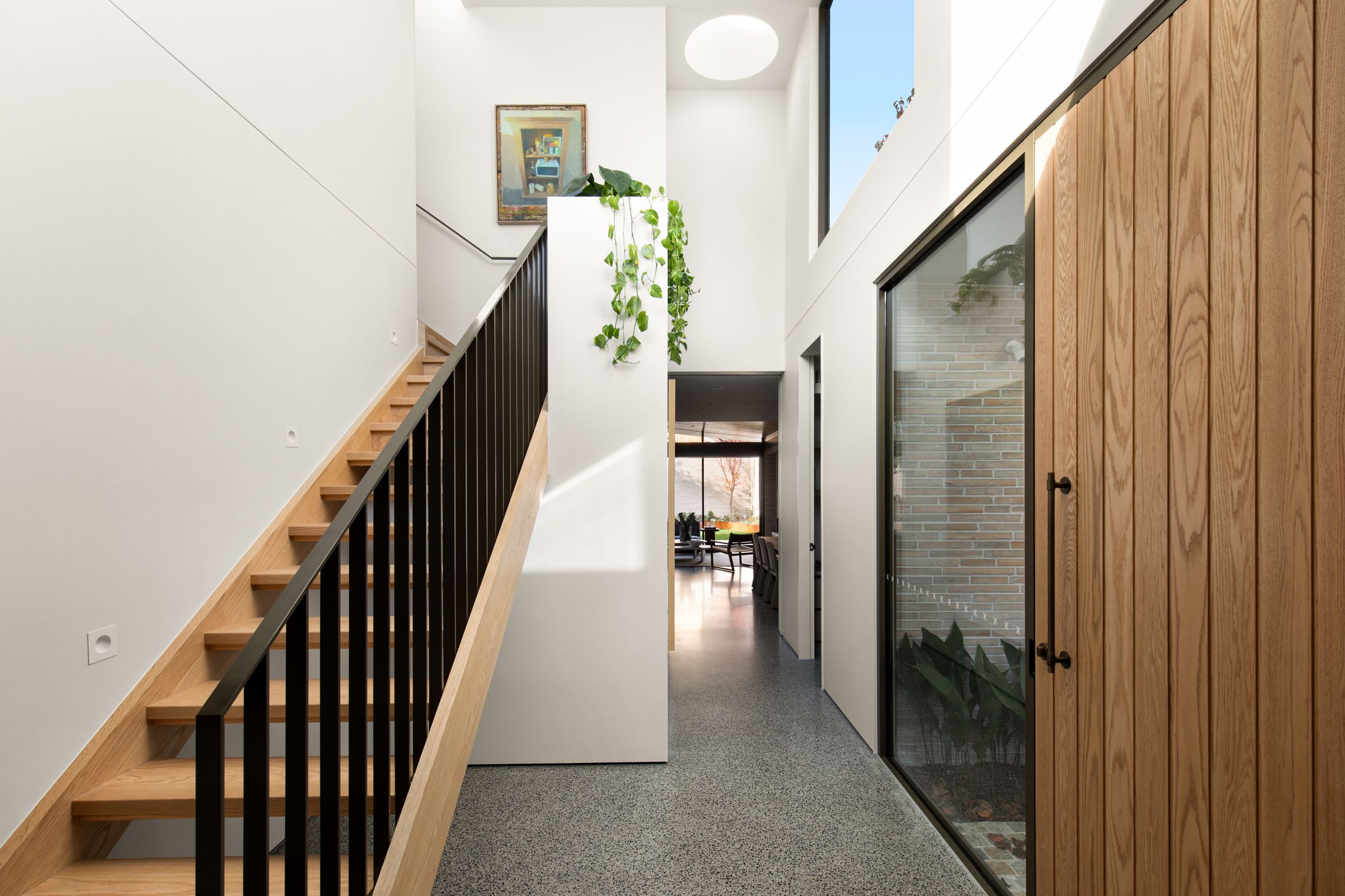 Entry hall with oak stair, round skylight and a glazed view into a planted lightwell