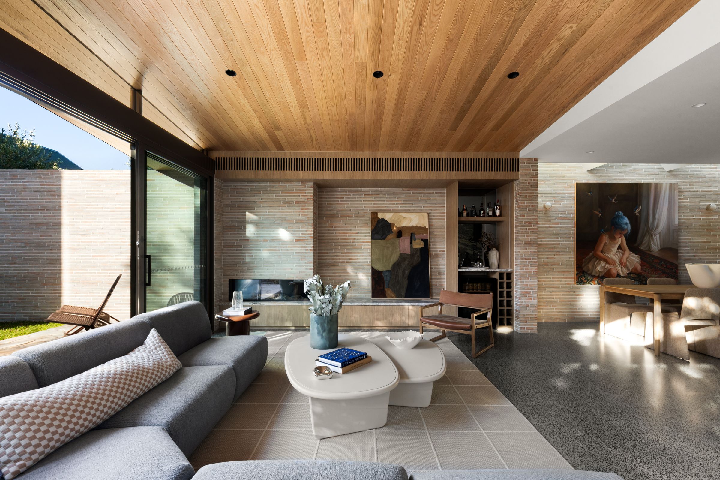Living room under the timber ceiling, with a brick fireplace and views to the courtyard