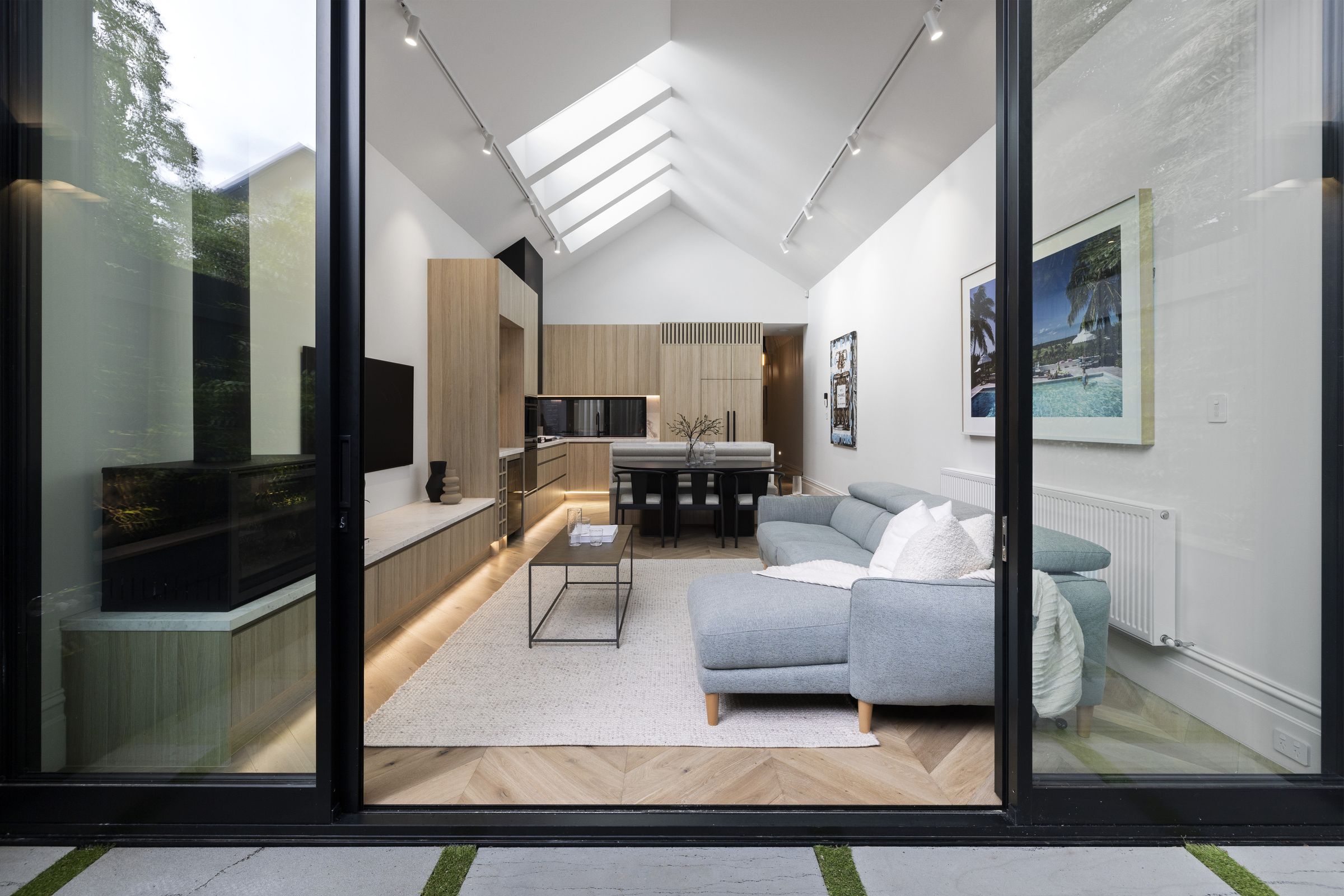 Henry seen from the courtyard through open sliding doors to the vaulted living, dining and kitchen