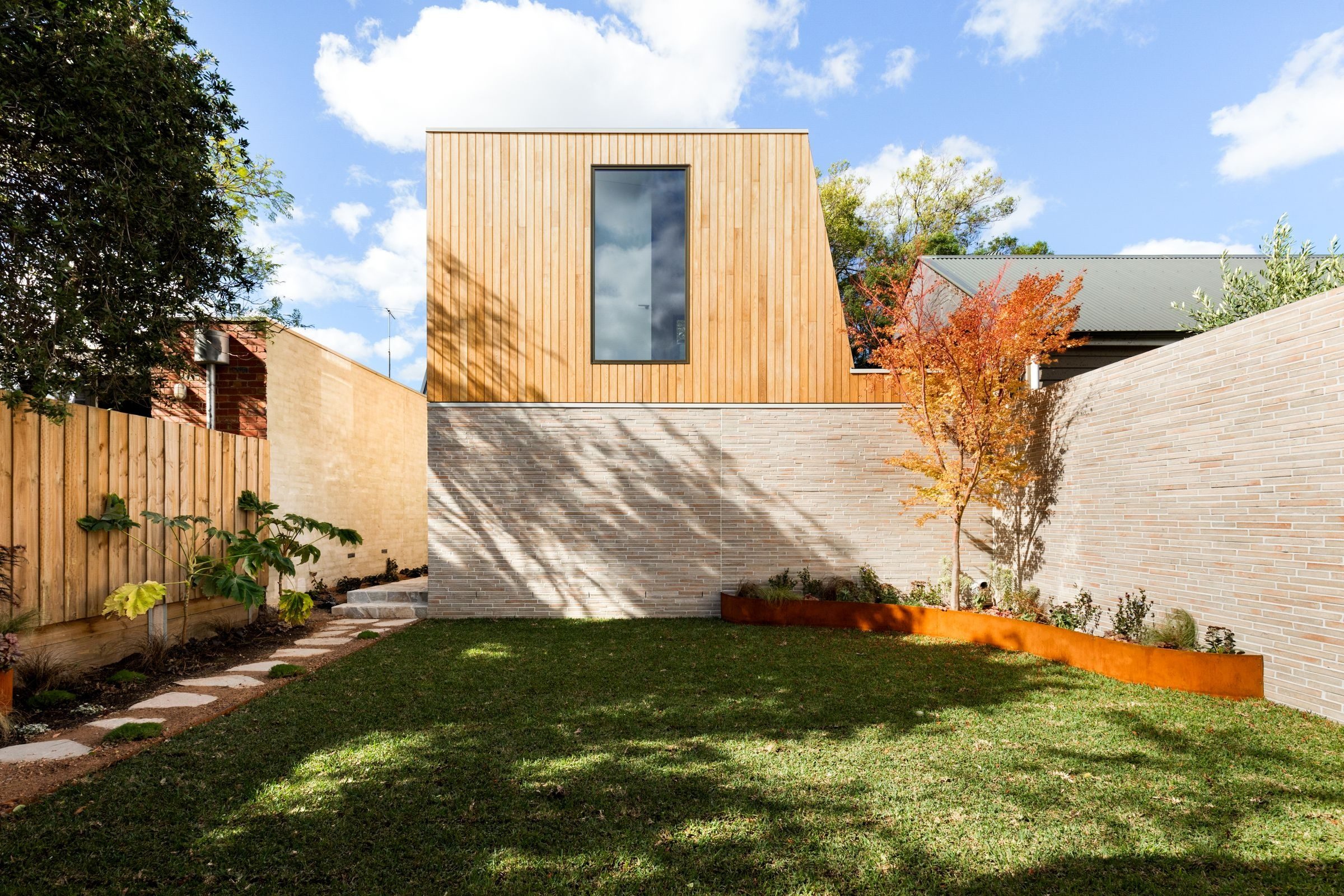 The rear of the house from the lawn: a timber-clad upper level over pale brick